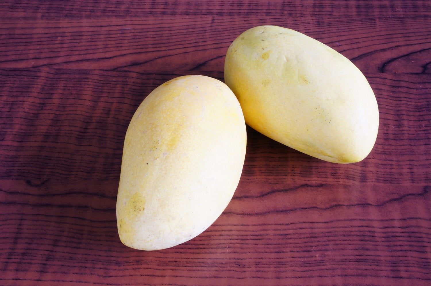 Two light yellow mangoes whole