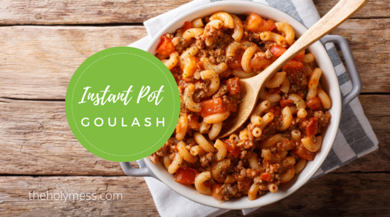 Instant Pot goulash in a white serving dish on a kitchen towel sitting on a wooden table top