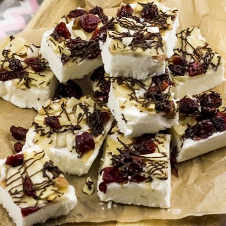 WW completed toasted almond cranberry yogurt bark pieces stacked on a sheet of parchment paper.