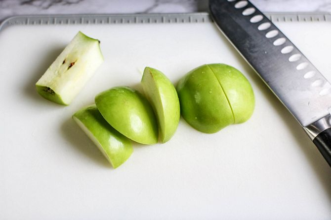 Green apples, sliced on white cutting board